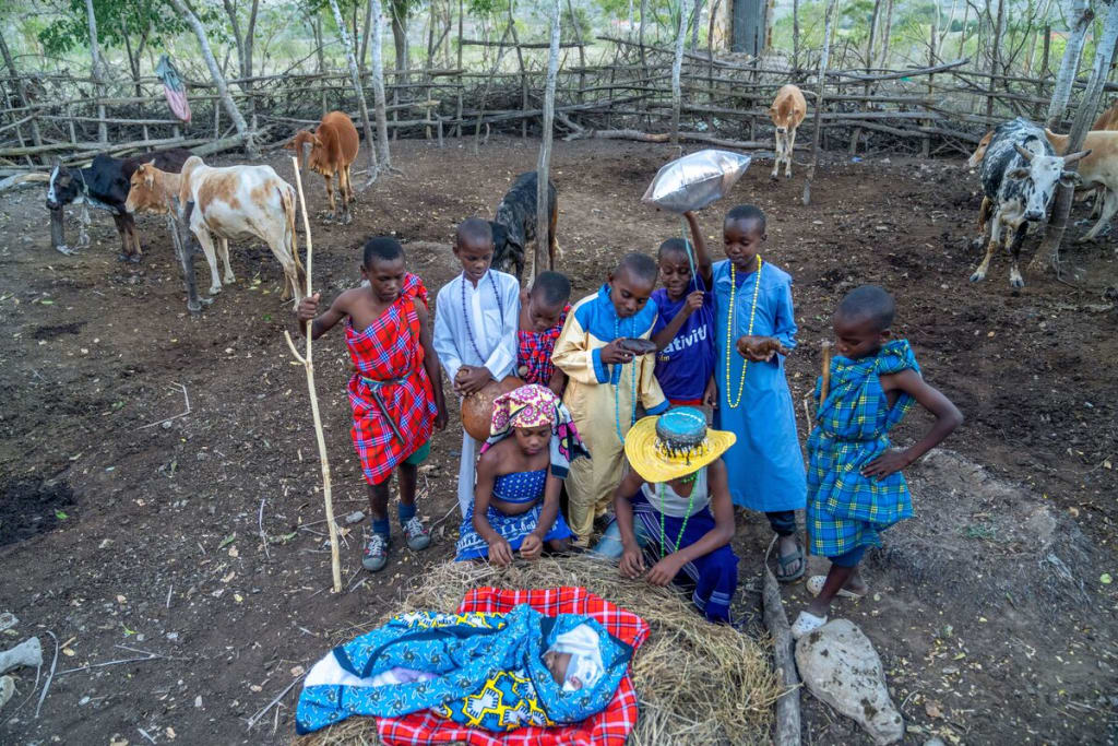 A group of children stand around an infant wrapped in blankets